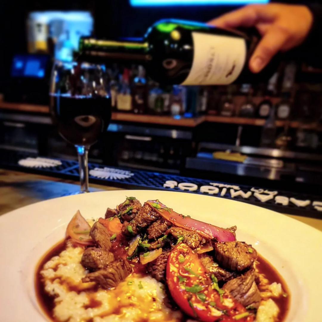 Red wine poured at the bar beside a plated steak