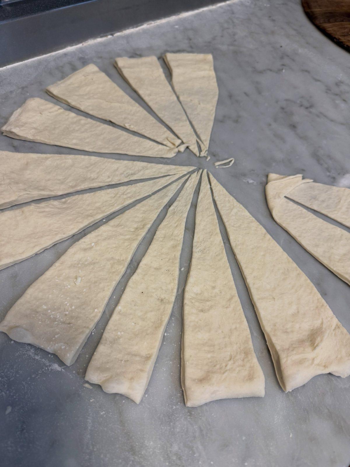 Fresh dough cut into wedges on a marble counter