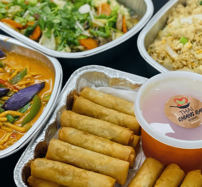 A takeout spread of curry, spring rolls, fried rice and salad