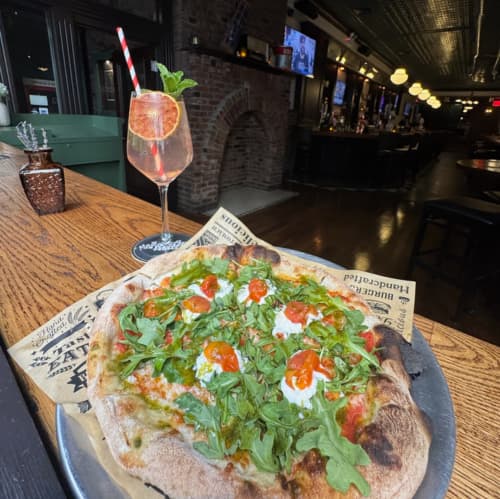 A pizza and a cocktail by the window