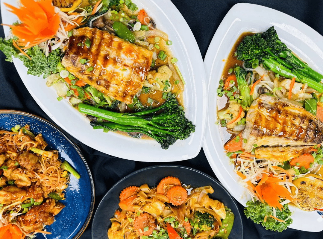 Grilled fish with stir-fried vegetables, next to noodle dishes