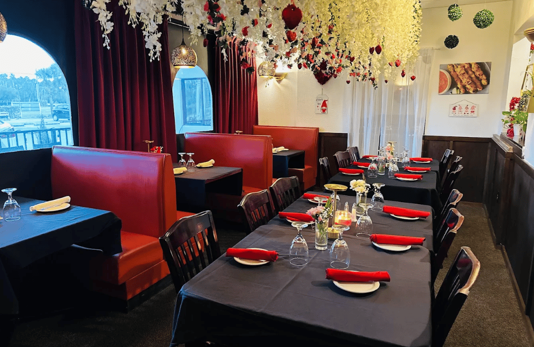 The Thai Chiang Rai dining room with red booths, black tablecloths and hanging white blossoms