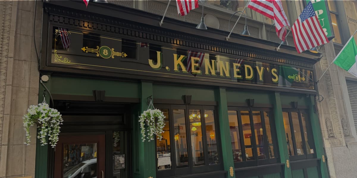 The J. Kennedy's storefront at 8 W 38th St, gold lettering above green windows and American flags