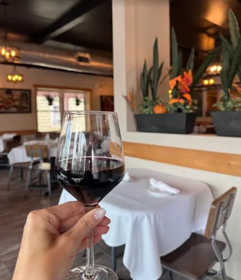 A glass of red wine raised in the dining room