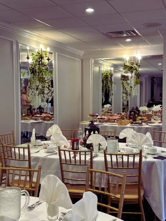 The banquet room set with white tablecloths and gold chairs