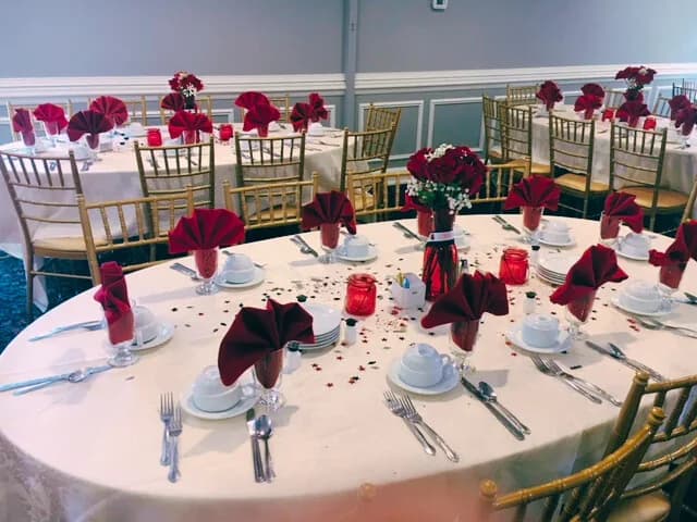 A round banquet table with red napkins and roses