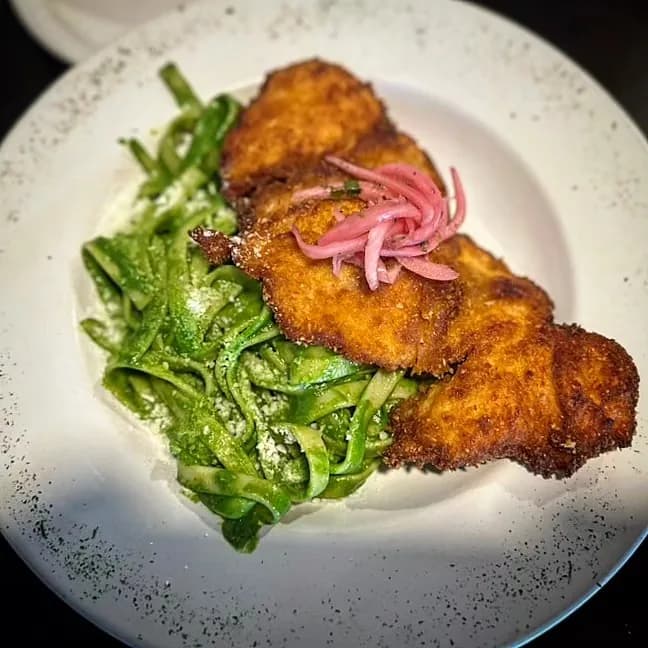 Crispy breaded cutlet with fresh greens and pickled onion