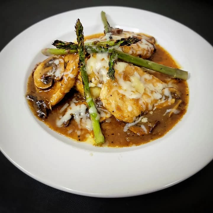 A plated entree with asparagus and mushrooms in a pan sauce