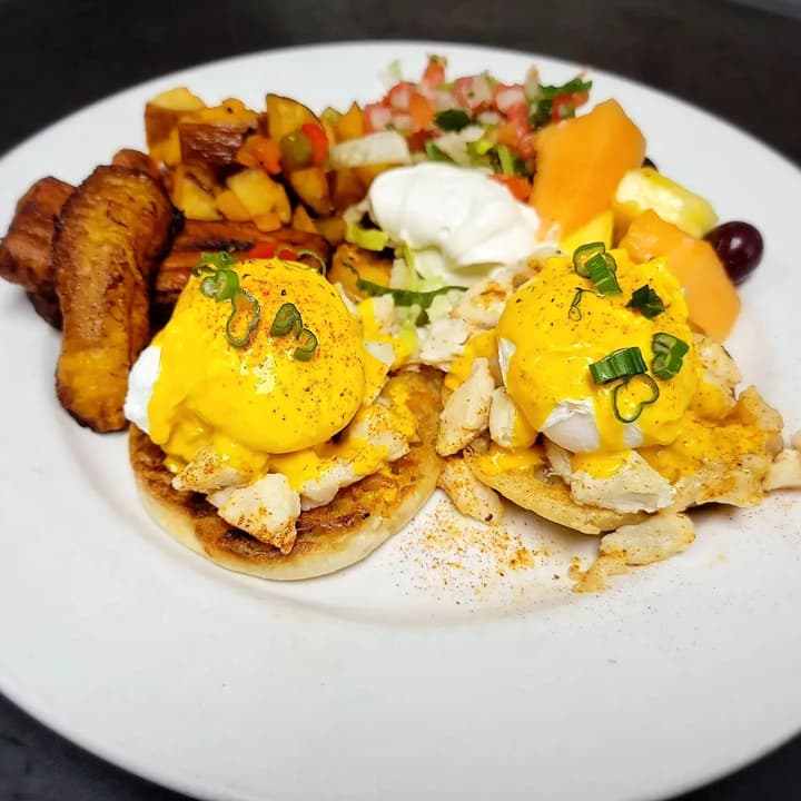 Eggs topped with hollandaise, with fried plantains and fruit