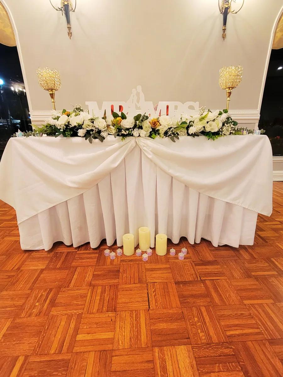 A head table dressed in white with flowers
