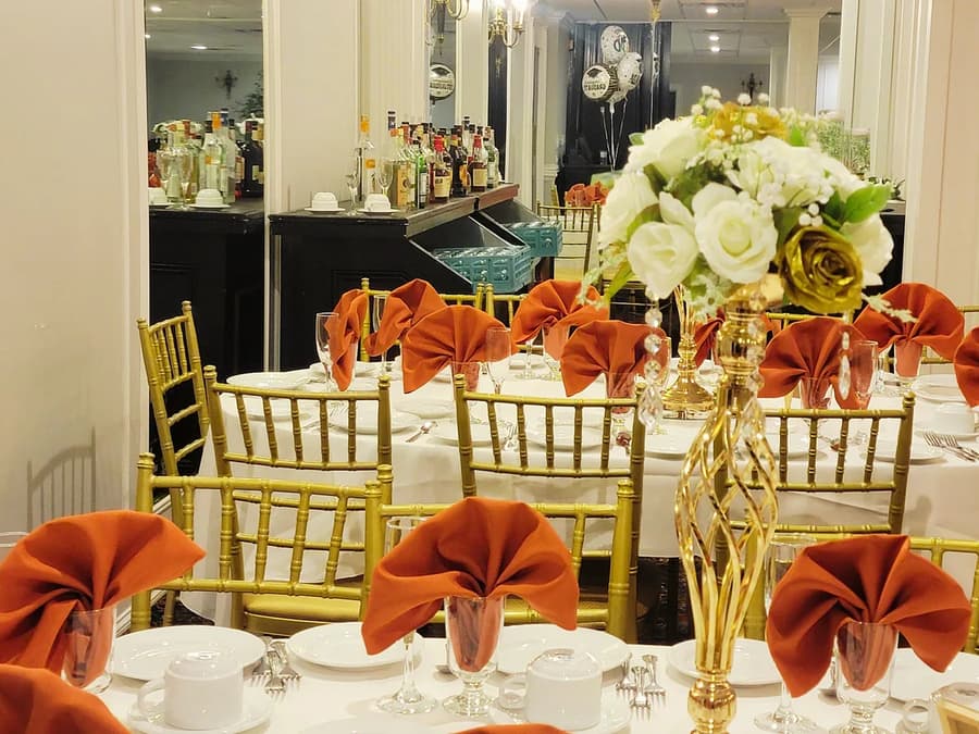 Wedding tables with orange napkins and gold centerpieces