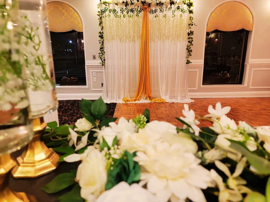 A flower arrangement and draped backdrop for a wedding