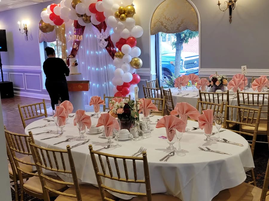 Tables with pink napkins under a balloon arch