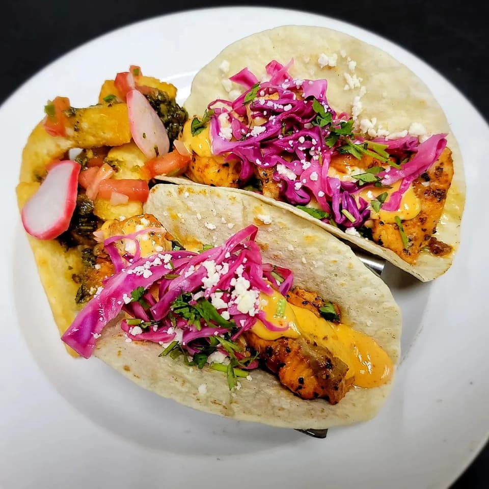 Three tacos with pickled red cabbage and crumbled cheese